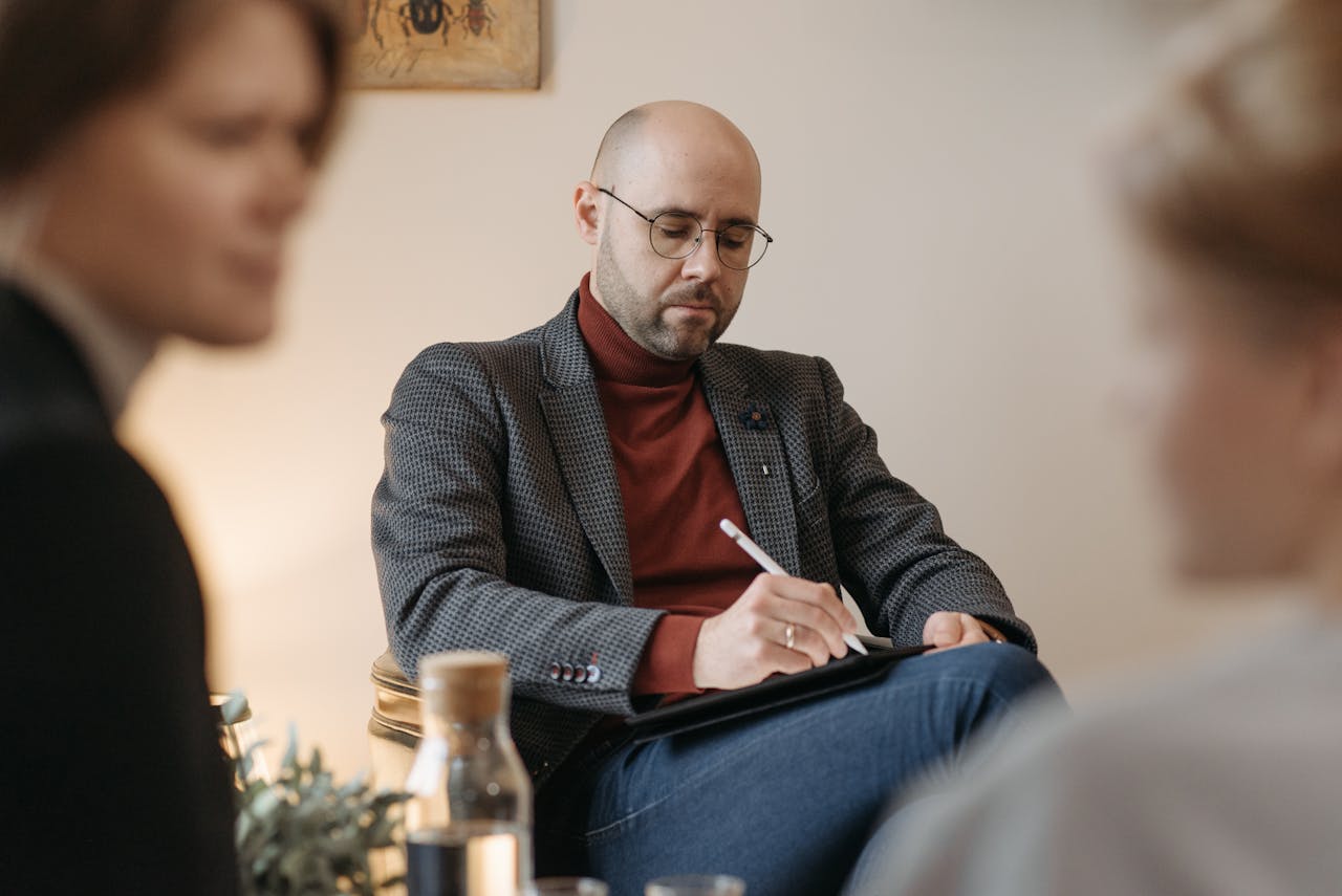 A consultant writing a note, while listening to the two ladies.