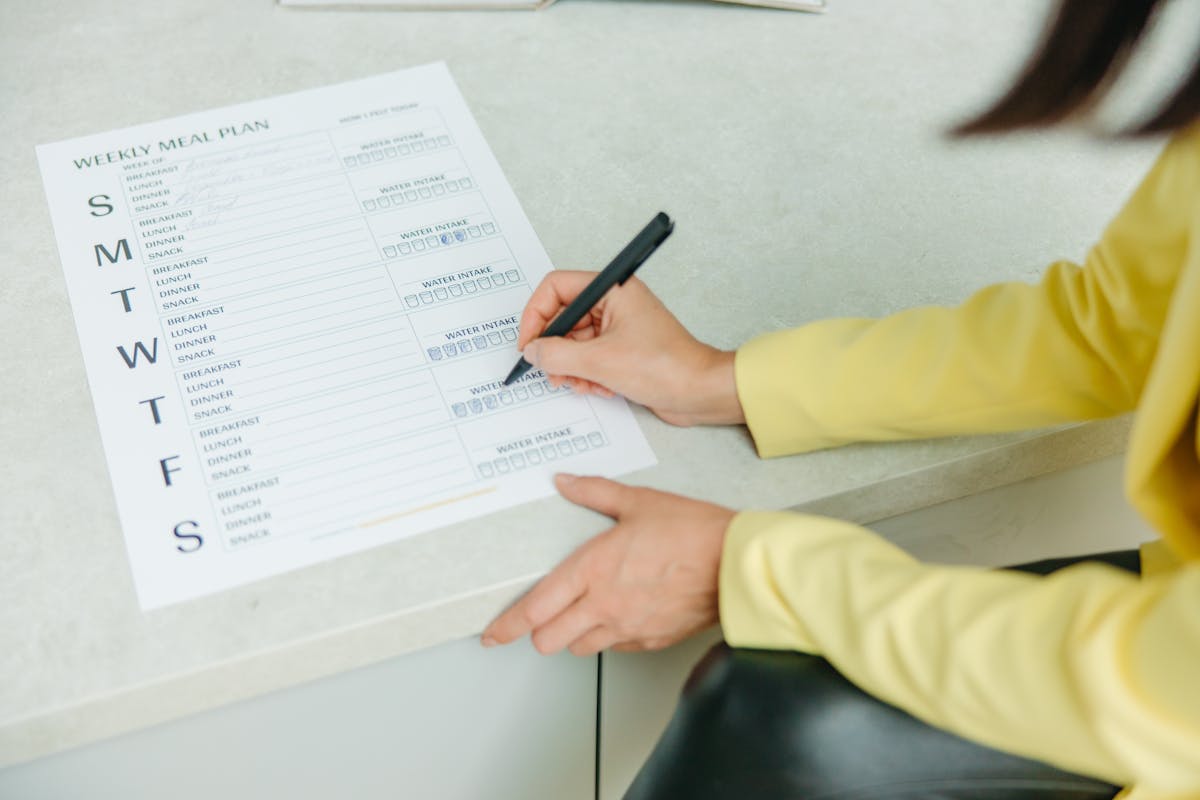 A nutrition coach writing a weekly meal plan on a paper.