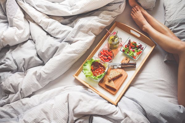 Breakfast in bed with assortments of vegetables, fruits and bread.