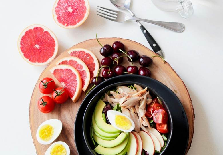 Assorted sliced fruits, veggies, egg and fish on the table.