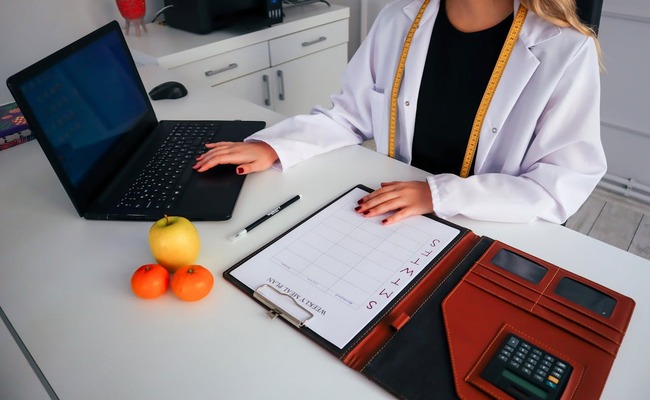 A nutrition coach preparing a guide for her client, showing the importance of proper training to nutrition coaches using different tools and training.